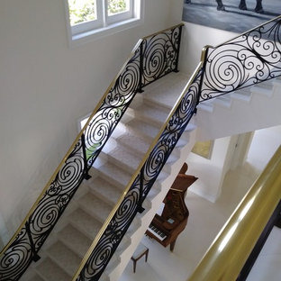 Immagine di una grande scala a "L" design con pedata in marmo, alzata in marmo e parapetto in metallo