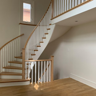 Ispirazione per una grande scala curva moderna con pedata in legno, alzata in legno verniciato e parapetto in legno