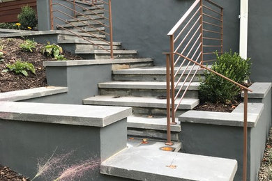 Inredning av en modern mellanstor trappa i kalk, med sättsteg i betong och räcke i metall