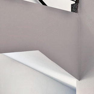Réalisation d'un grand escalier droit minimaliste avec des marches en carrelage, des contremarches en carrelage, un garde-corps en verre et un mur en parement de brique.