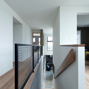 Exemple d'un escalier droit moderne avec des marches en bois, des contremarches en béton, un garde-corps en métal et un mur en parement de brique.