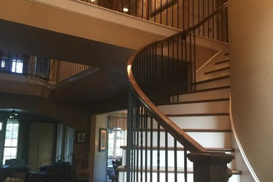 Foto de escalera curva actual grande con escalones de madera, contrahuellas de madera pintada y barandilla de metal