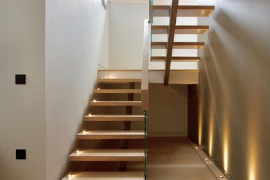 Foto de escalera suspendida contemporánea grande sin contrahuella con escalones de madera y barandilla de madera