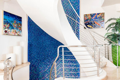 Ejemplo de escalera de caracol actual grande con barandilla de metal, escalones con baldosas y contrahuellas con baldosas y/o azulejos
