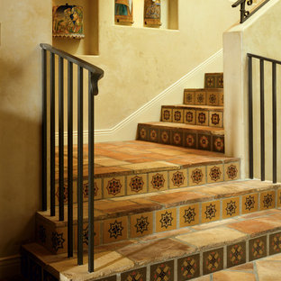 Foto di una scala mediterranea con pedata in terracotta, alzata piastrellata e parapetto in metallo