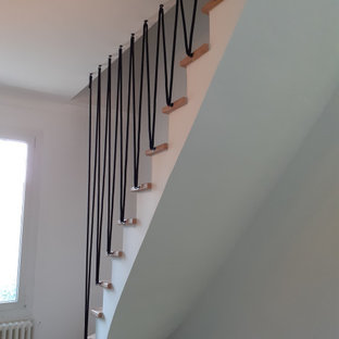 Cette photo montre un petit escalier courbe scandinave avec des marches en bois, des contremarches en béton et un garde-corps en verre.
