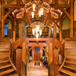 Huge mountain style wooden curved staircase photo in Jackson with wooden risers