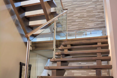 Imagen de escalera en U moderna sin contrahuella con escalones de madera y barandilla de vidrio