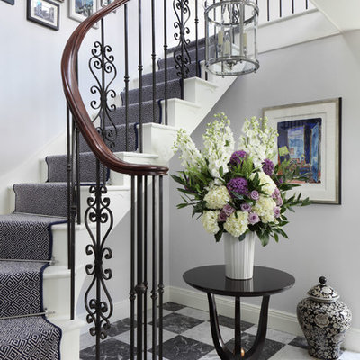 Mid-sized elegant painted curved staircase photo in London with painted risers