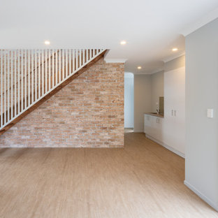 Idee per una grande scala a rampa dritta costiera con pedata in legno, alzata in legno, parapetto in legno e pareti in mattoni