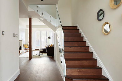 Medium sized contemporary wood staircase in London with wood risers and feature lighting.
