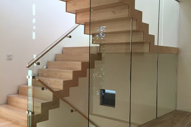 Medium sized modern wood u-shaped staircase in Edmonton with wood risers.