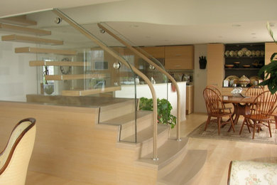 Diseño de escalera recta actual de tamaño medio con escalones de madera, barandilla de vidrio y contrahuellas de madera