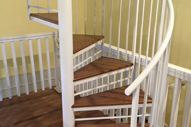 Foto de escalera de caracol clásica sin contrahuella con escalones de madera y barandilla de metal