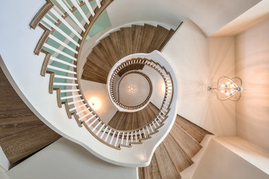 Example of a large beach style wooden curved staircase design in Miami with painted risers