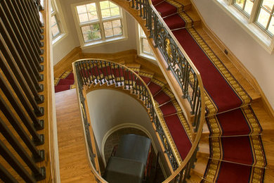 Пример оригинального дизайна: огромная винтовая лестница в классическом стиле с ступенями с ковровым покрытием и перилами из смешанных материалов