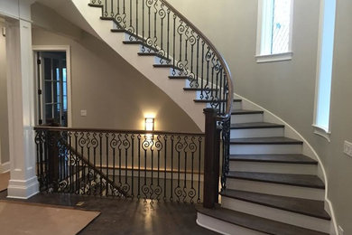 Ejemplo de escalera curva clásica renovada grande con escalones de madera, contrahuellas de madera pintada y barandilla de varios materiales