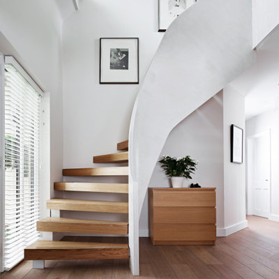 Staircase - large contemporary wooden curved open staircase idea in Wiltshire