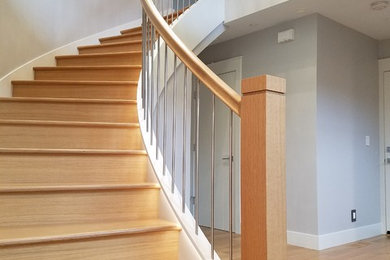 Exemple d'un grand escalier courbe tendance avec des marches en bois, des contremarches en bois et un garde-corps en matériaux mixtes.