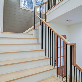 Idée de décoration pour un grand escalier champêtre en U avec des marches en bois, des contremarches en bois peint, un garde-corps en bois et du lambris.