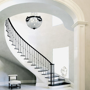 Immagine di una grande scala curva chic con alzata in legno verniciato, parapetto in metallo e pedata in legno