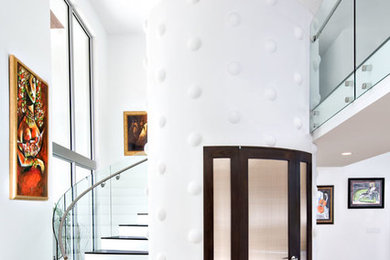 Ejemplo de escalera curva minimalista de tamaño medio con escalones de madera, contrahuellas de madera pintada y barandilla de vidrio