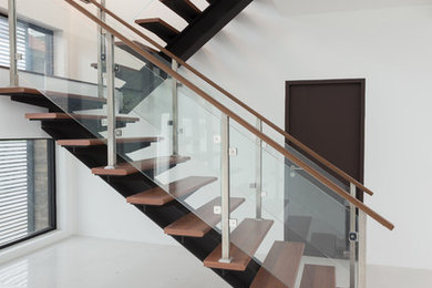 Ejemplo de escalera en U contemporánea sin contrahuella con barandilla de vidrio y escalones de madera