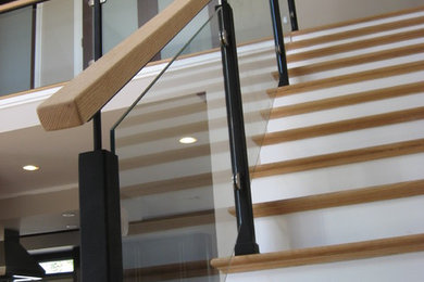 Diseño de escalera recta actual de tamaño medio con escalones de madera y contrahuellas de madera pintada