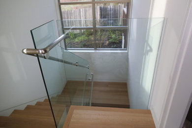 Foto de escalera en U contemporánea de tamaño medio con escalones de madera, contrahuellas de madera y barandilla de vidrio
