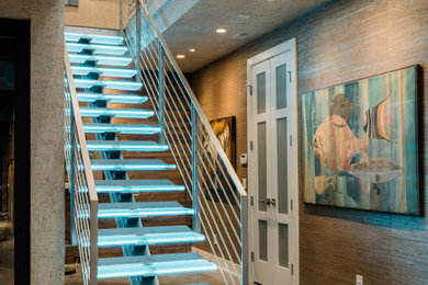 На фото: большая лестница на больцах в стиле модернизм с стеклянными ступенями, металлическими перилами и обоями на стенах без подступенок