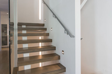 Idée de décoration pour un escalier flottant minimaliste avec des marches en bois, des contremarches en bois et un garde-corps en verre.