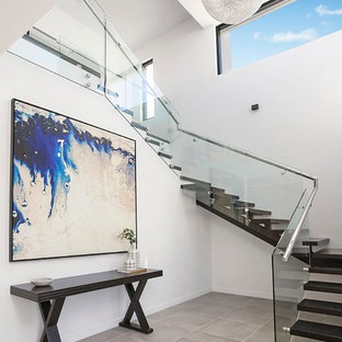 This is an example of a contemporary wood u-shaped staircase in Sydney with glass railing and open risers.