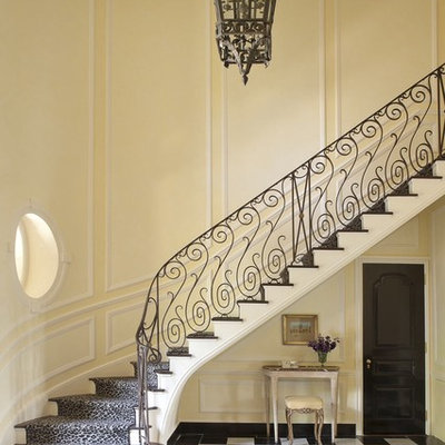 Elegant wooden curved staircase photo in New York with painted risers