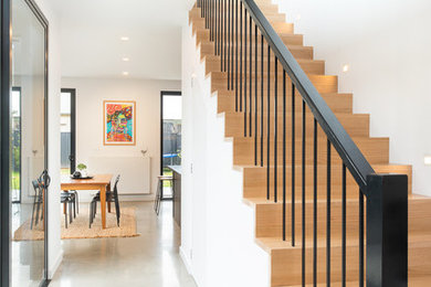 Diseño de escalera recta actual de tamaño medio con escalones de madera, contrahuellas de madera y barandilla de metal