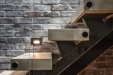 Imagen de escalera en U urbana grande sin contrahuella con escalones de madera y barandilla de vidrio