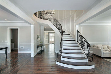 Ejemplo de escalera curva clásica de tamaño medio con escalones de madera, contrahuellas de madera pintada y barandilla de madera