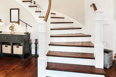 Diseño de escalera curva clásica renovada con escalones de madera, contrahuellas de madera pintada y barandilla de madera