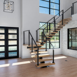 Foto di un'ampia scala sospesa moderna con pedata in legno, nessuna alzata e parapetto in cavi
