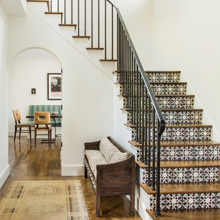Aménagement d'un escalier méditerranéen en L avec des marches en bois, des contremarches en carrelage et un garde-corps en métal.