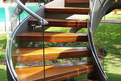 Ejemplo de escalera contemporánea sin contrahuella con escalones de madera y barandilla de metal