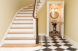 Diseño de escalera curva clásica grande con escalones de madera, contrahuellas de madera pintada y barandilla de madera