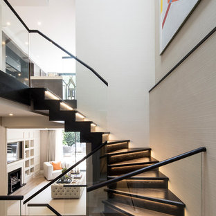 This is an example of a medium sized contemporary wood u-shaped glass railing staircase in London with wood risers.