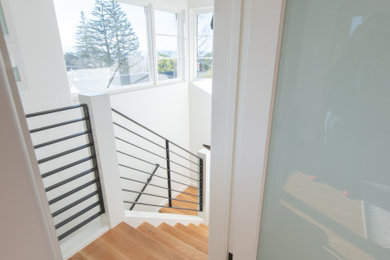 Imagen de escalera en U actual de tamaño medio con escalones de madera, contrahuellas de madera y barandilla de metal
