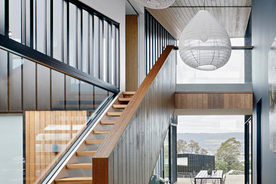 Ejemplo de escalera recta minimalista grande sin contrahuella con escalones de madera y barandilla de madera