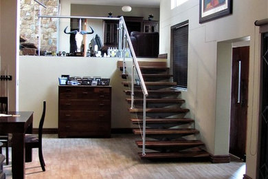 Diseño de escalera suspendida minimalista grande con escalones de metal, contrahuellas de madera y barandilla de metal