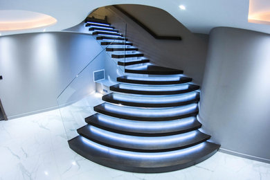 Illuminated floating staircase with huge curved treads