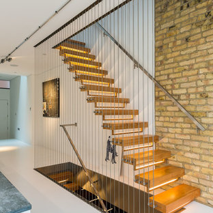 Design ideas for a medium sized contemporary wood wire cable railing staircase in London with open risers.