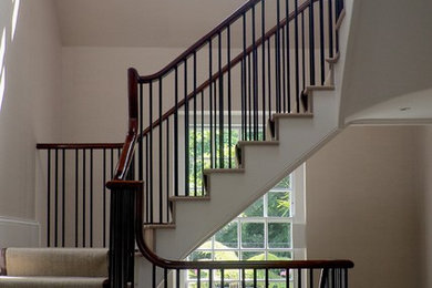 This is an example of a large contemporary carpeted curved staircase in London with carpeted risers.