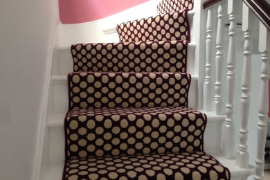 Foto de escalera en U contemporánea de tamaño medio con escalones enmoquetados, contrahuellas enmoquetadas y barandilla de madera