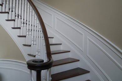 Ejemplo de escalera curva clásica de tamaño medio con escalones de madera, contrahuellas de madera pintada y barandilla de madera